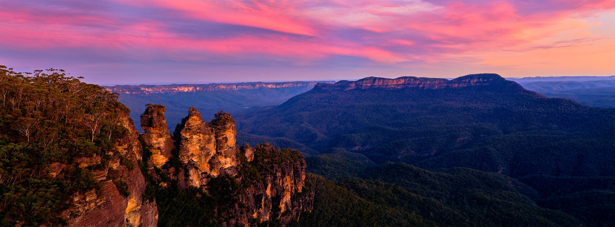 Three Sisters at the Blue Mountains, New South Wales, beneath vivid pink and violet clouds — panorama by Mitchell Burns